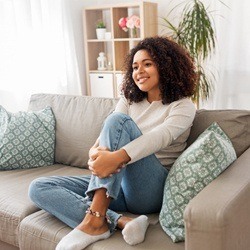 person smiling and sitting on a couch periodontal therapy