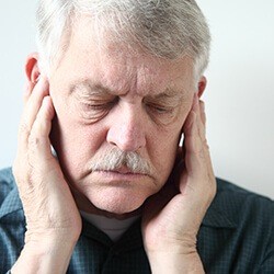 Elderly man holding jaw in pain before TMJ therapy
