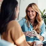 Two friends smiling while enjoying cup of coffee together