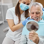a patient checking his new teeth with a mirror
