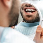 Man smiling at reflection in handheld mirror