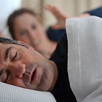 man sleep next to irritated wife 