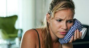 Woman holding ice pack next to toothache