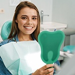 Woman smiling while using dental mirror