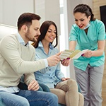 dental team member showing paperwork to two patients