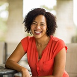 Curly-haired woman in red shirt smiling while outside