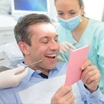 Man looking at smile in mirror after implant denture placement