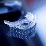 A top and bottom Invisalign aligner sitting on a table near a protective case