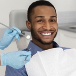 A young male smiling while preparing to have his teeth checked by a dental professional