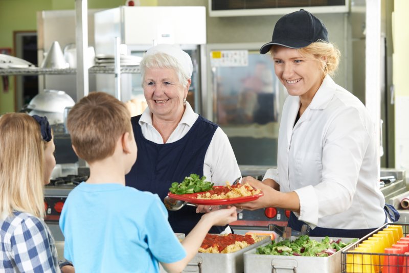 Kids in line to get their school lunch, smiling with their healthy teeth