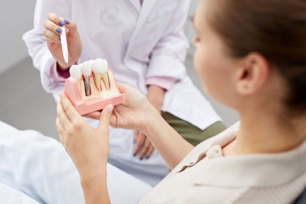 A dentist showing a patient a model of a dental implant