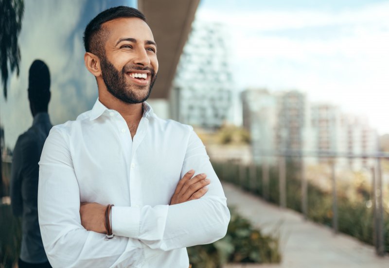 Patient smiling on top of building after cosmetic dentistry